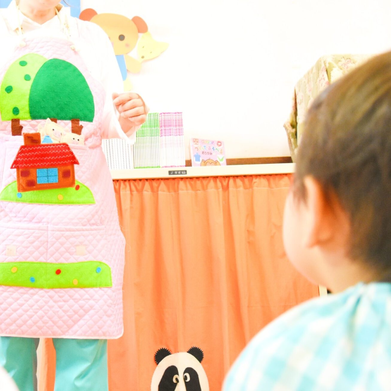 すずらん幼児園でエプロンシアターを見つめる子どもたちの様子。先生が動物の人形を使ってお話をしています。