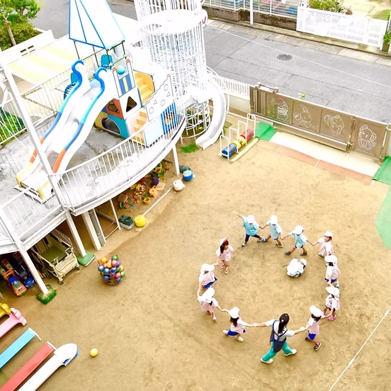すずらん幼児園の広い園庭で遊具ではしゃぐ子どもたち