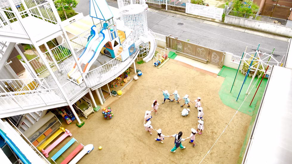すずらん幼児園の広い園庭で遊具ではしゃぐ子どもたち
