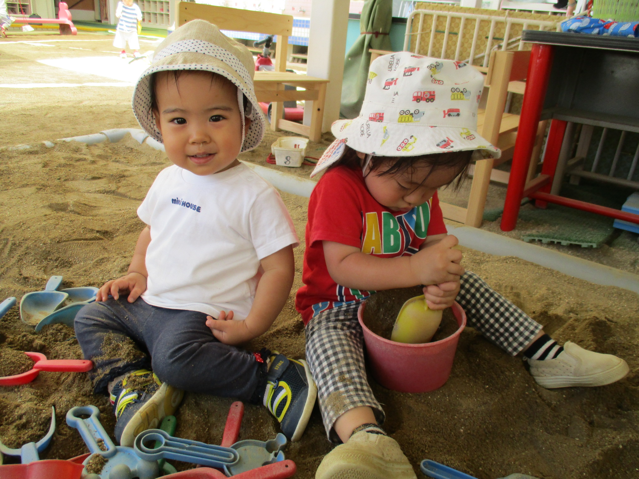 すずらん幼児園の砂場で、スコップやバケツを使って遊ぶ小さな子どもたち。好奇心いっぱいの表情が印象的。