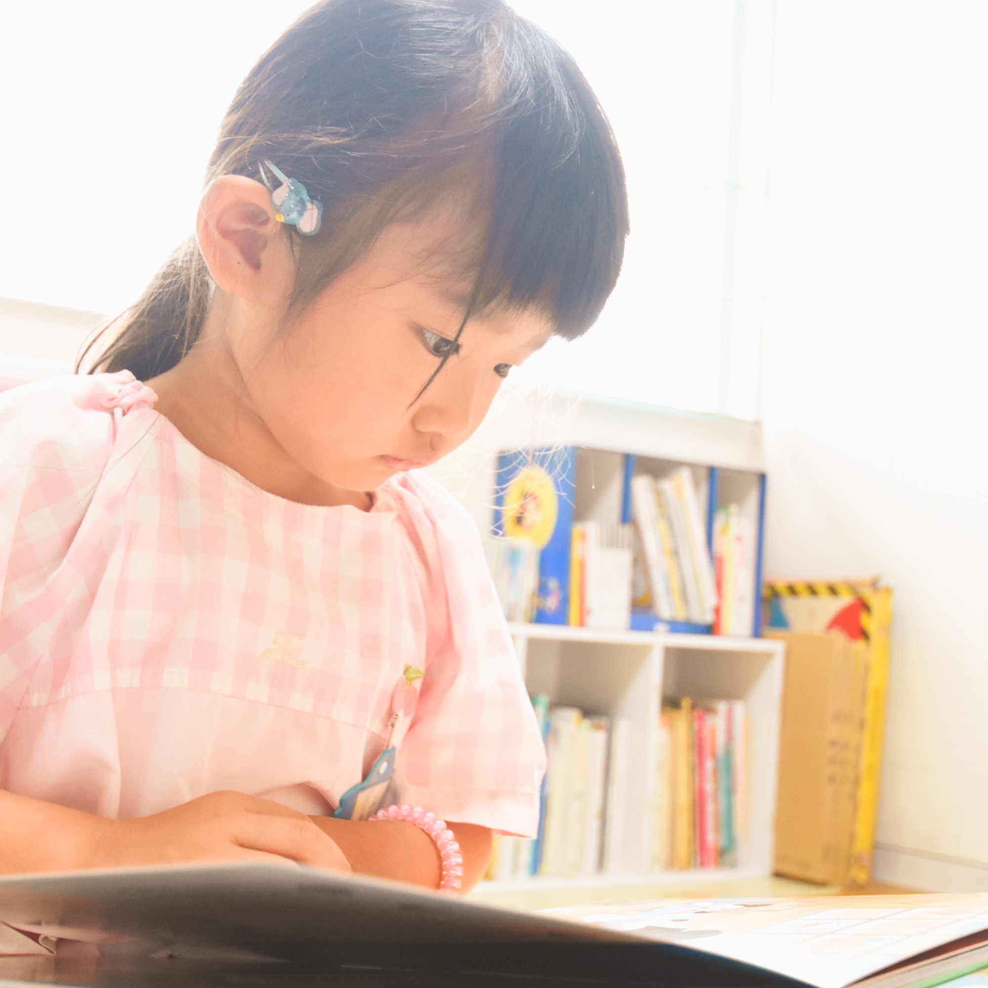 すずらん幼児園の教室で、本に集中している女の子。静かな学びの時間を過ごす様子。